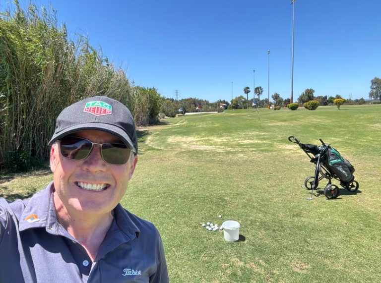 man with golf bag on driving range